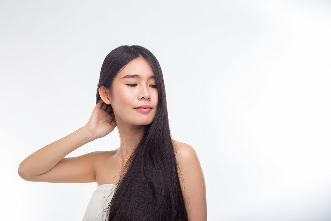 Asian woman wearing strapless white top combing her hands through her hair